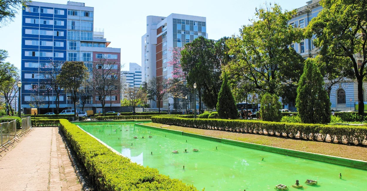 Praça da Liberdade em Belo Horizonte com espelho d’água verde, jardins e prédios modernos ao redor