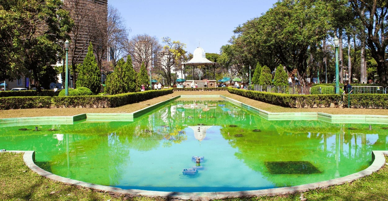 Espelho d’água na Praça da Liberdade em Belo Horizonte com jardim, árvores e coreto ao fundo