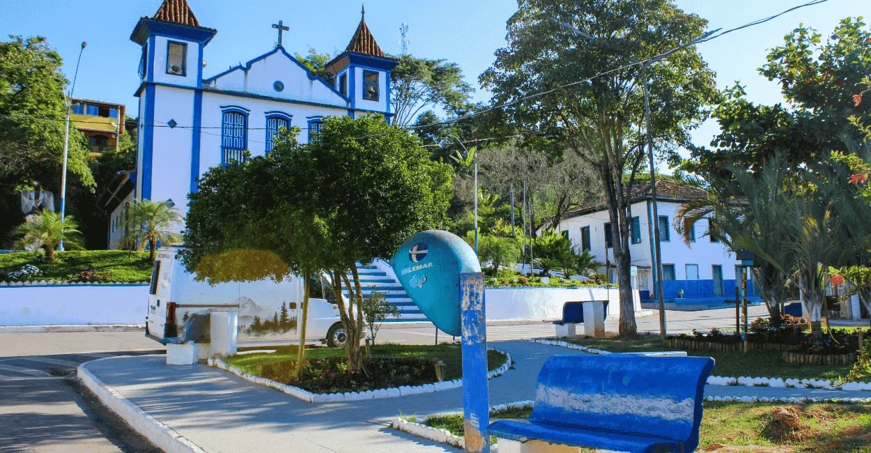 Igreja histórica e praça central de Ipoema com fachadas brancas e azuis em cenário tranquilo