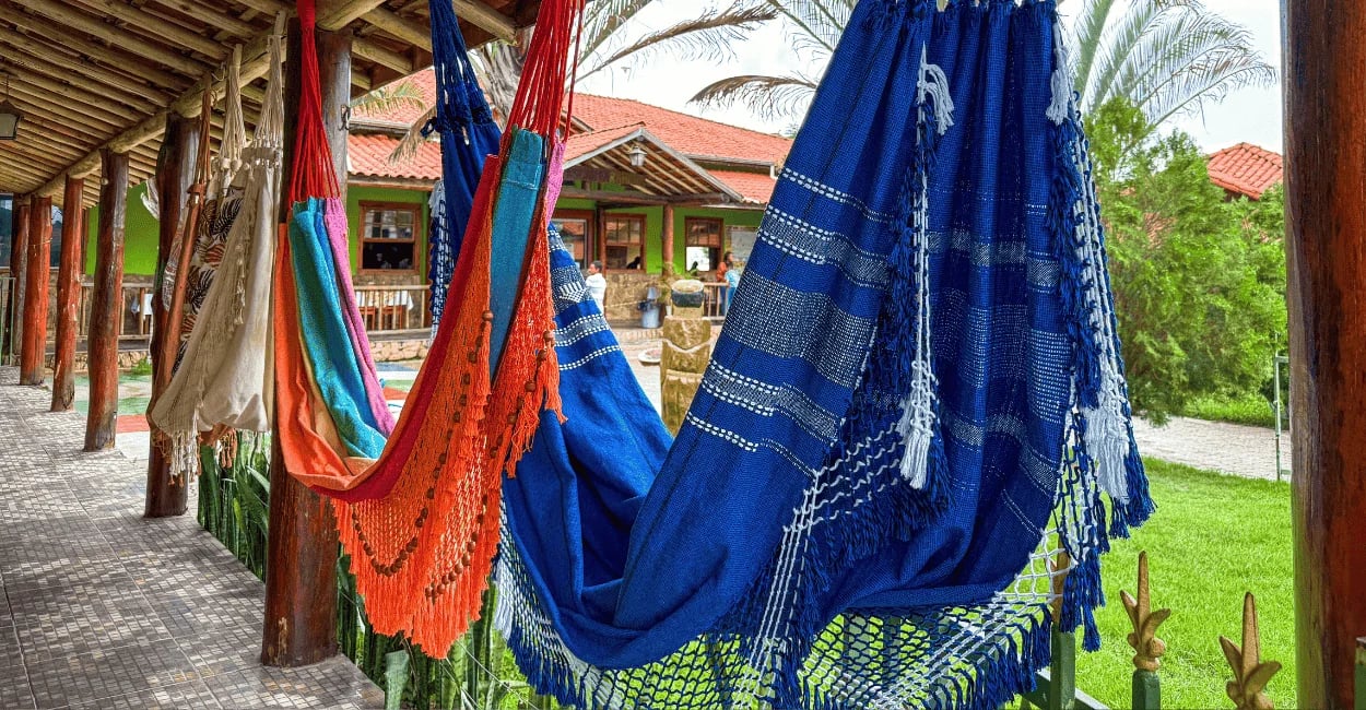 Redes artesanais coloridas em Resende Costa com varanda rústica, jardim verde e arquitetura gentil