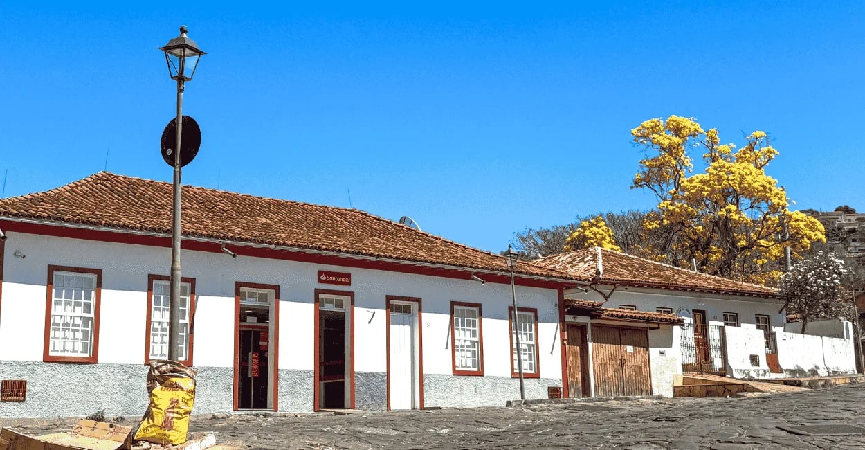 Casarão colonial tradicional com um ipê-amarelo florido ao fundo em Diamantina