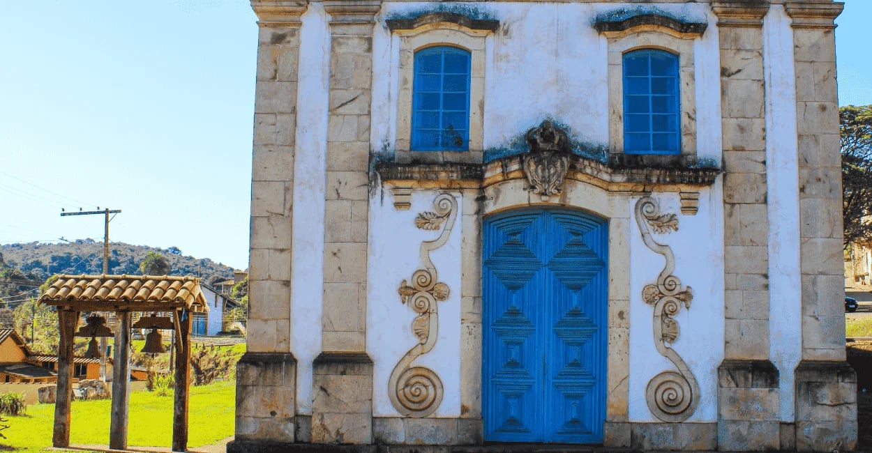 Capela histórica com porta azul e sino ao lado em Lobo Leite, distrito de Congonhas, Minas Gerais