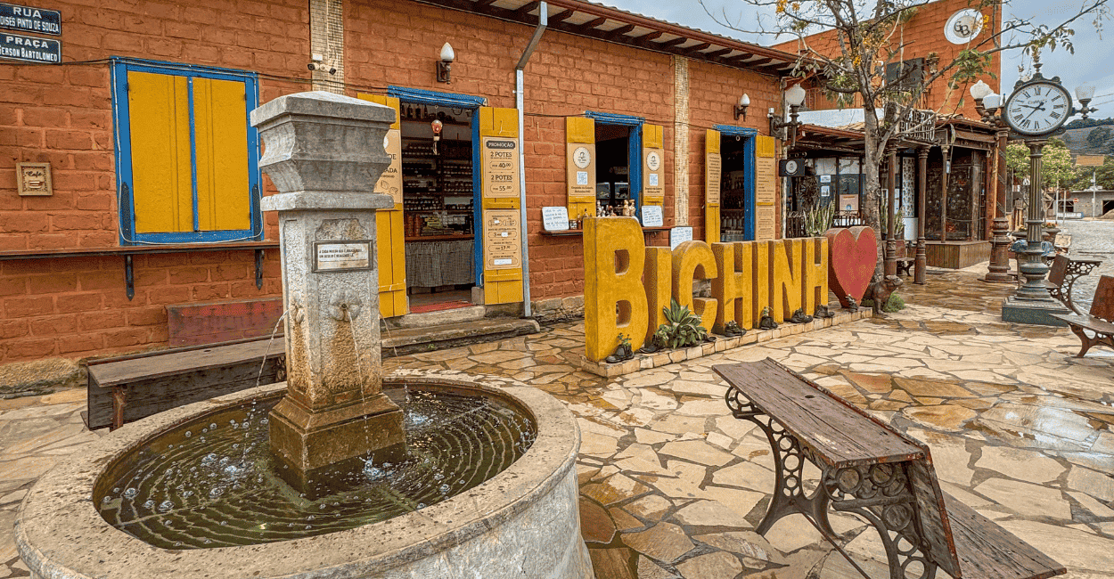 Uma fonte com um banco ao lado e um letreiro eu amo Bichinho, dsitrito de Prados MG