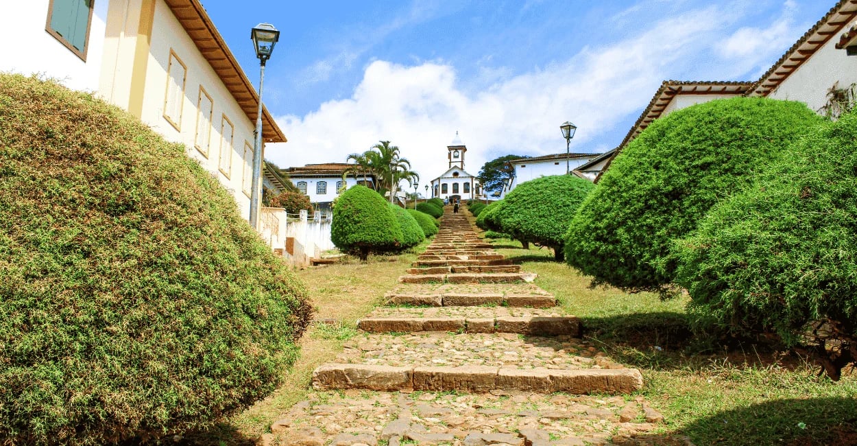 Escadaria da Igreja Santa Rita no Serro MG com caminho de pedras, jardins e igreja ao fundo