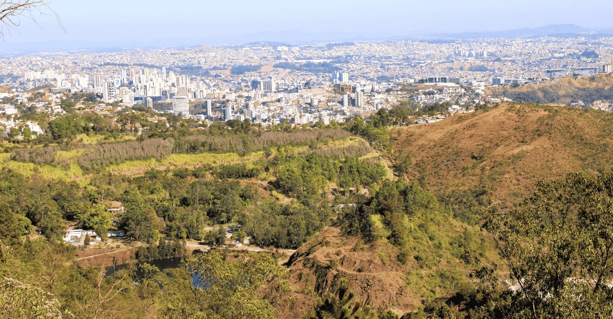 Vista panorâmica de Belo Horizonte a partir do Mirante da Serra do Curral, com montanhas e área verd