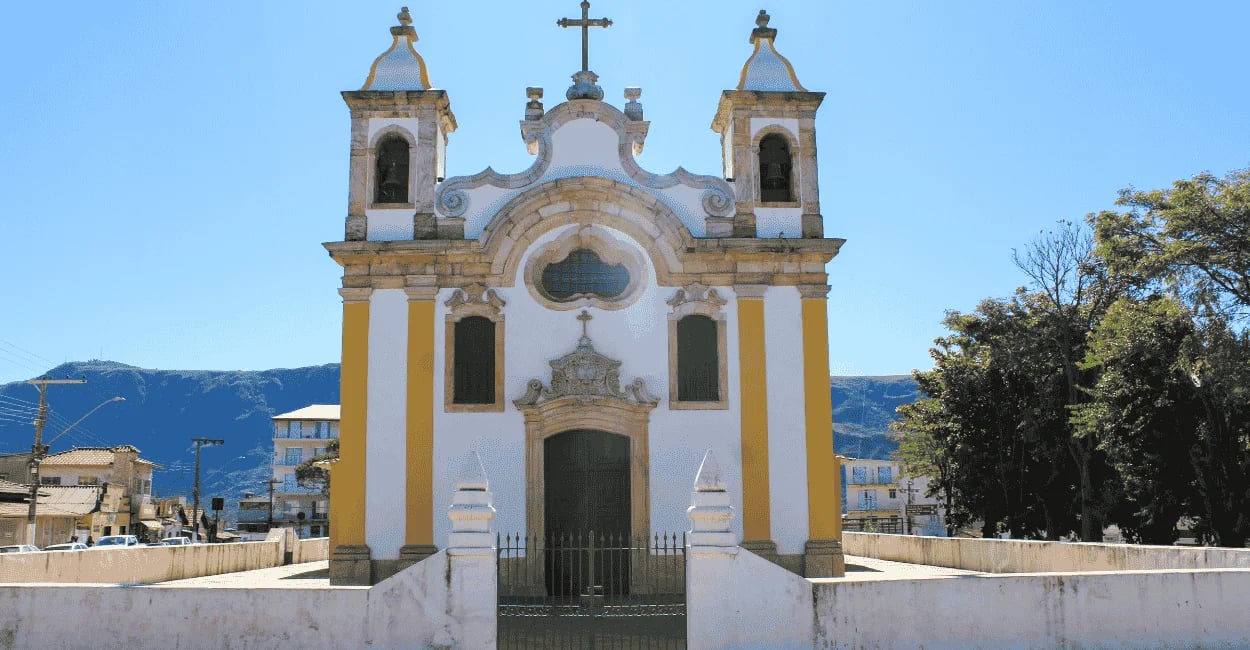 Fachada histórica de igreja com duas torres sineiras e detalhes em pedra. Ouro Branco