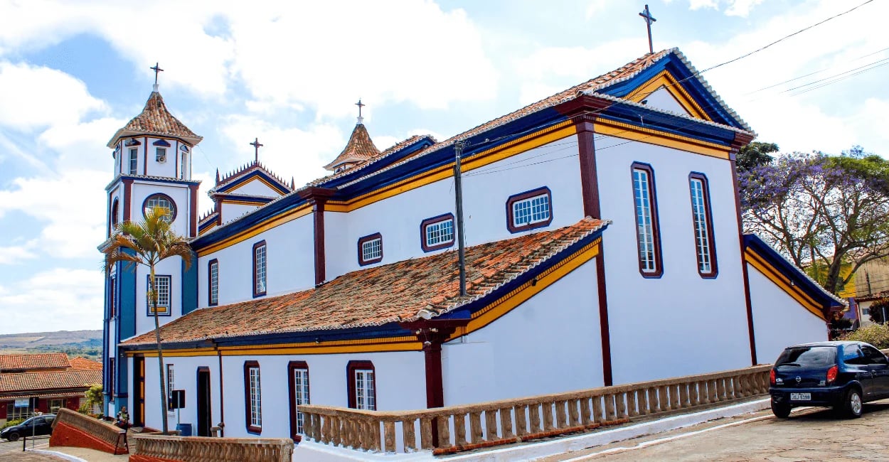 Vista lateral da Igreja Matriz de Datas, em Minas Gerais, com fachada colorida e telhado colonial