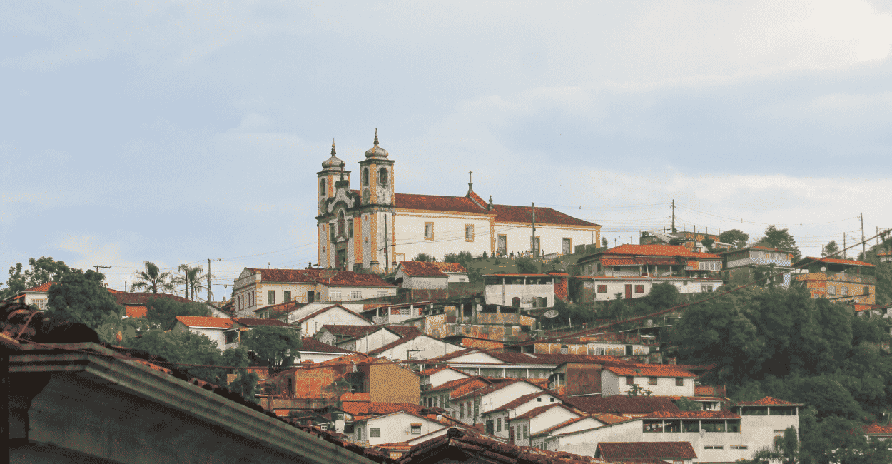 Vista panoramica da Igreja de Santa Efigênia em Ouro Preto, com casas em volta e céu nublado