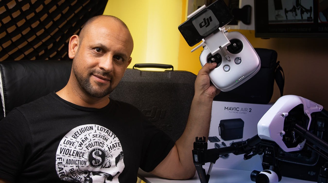 Una persona posando para la camara con su drone DJI en su mano izquierda