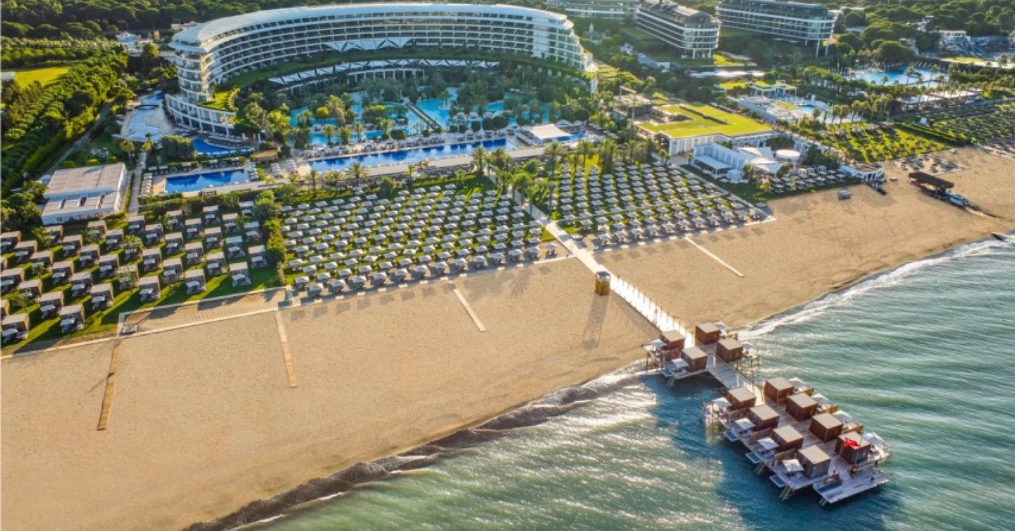 Maxx Royal luxury resort with swimming pools, private cabanas, and a wooden pier over the ocean.