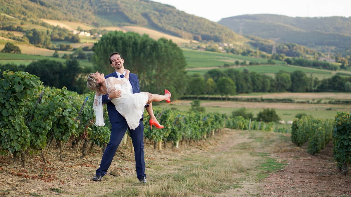Photography of a vineyard landscape in burgundy france with the groom holding the bride in his arms.