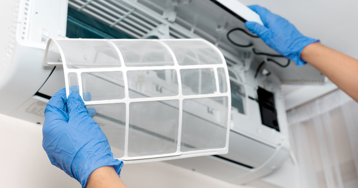 Una persona con guantes sosteniendo un filtro de aire acondicionado