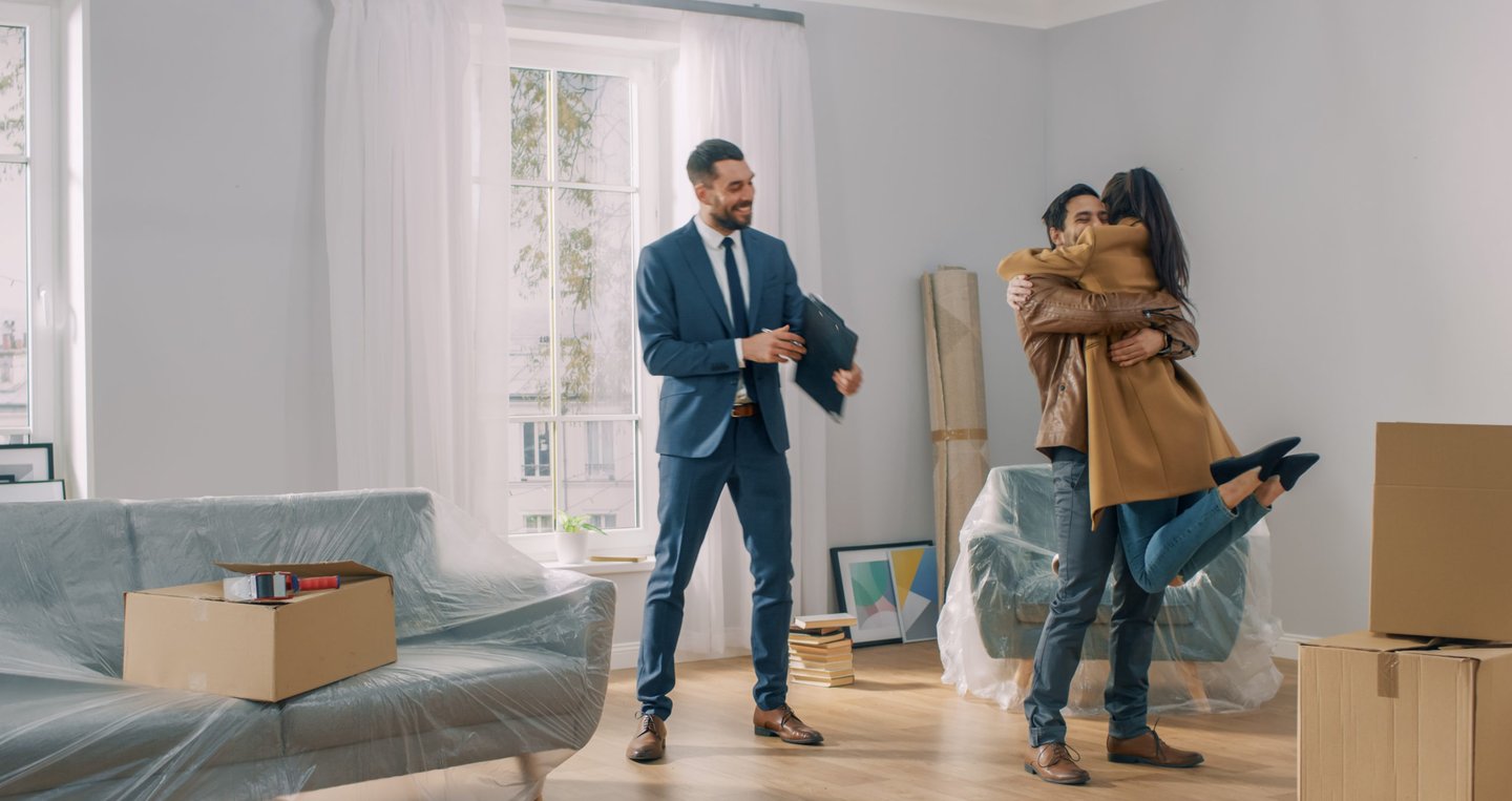 Casal feliz com a casa nova alugada e seu corretor de imóveis.