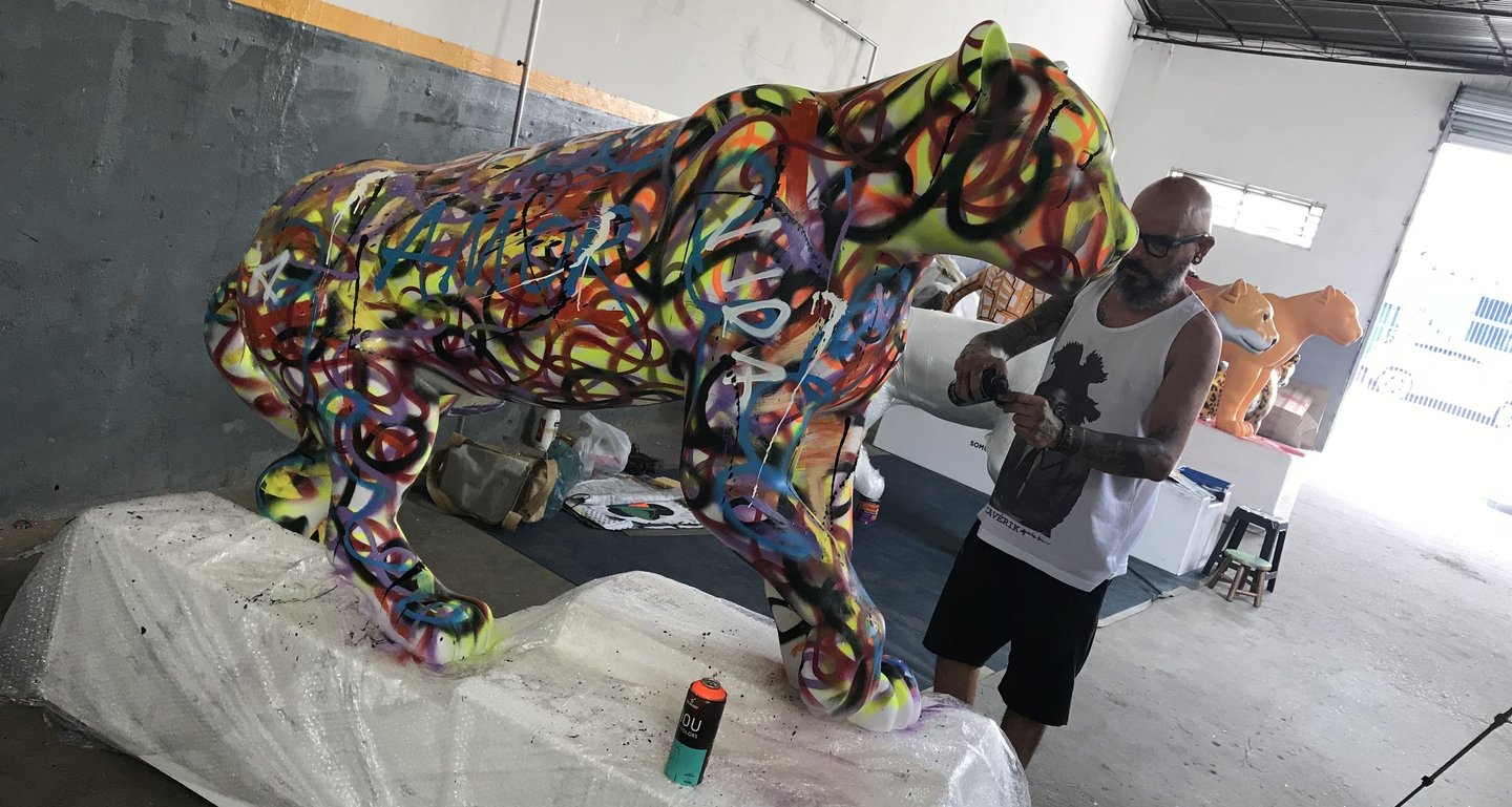 érgio Astral posando ao lado de sua criação, uma escultura de onça-pintada estilizada