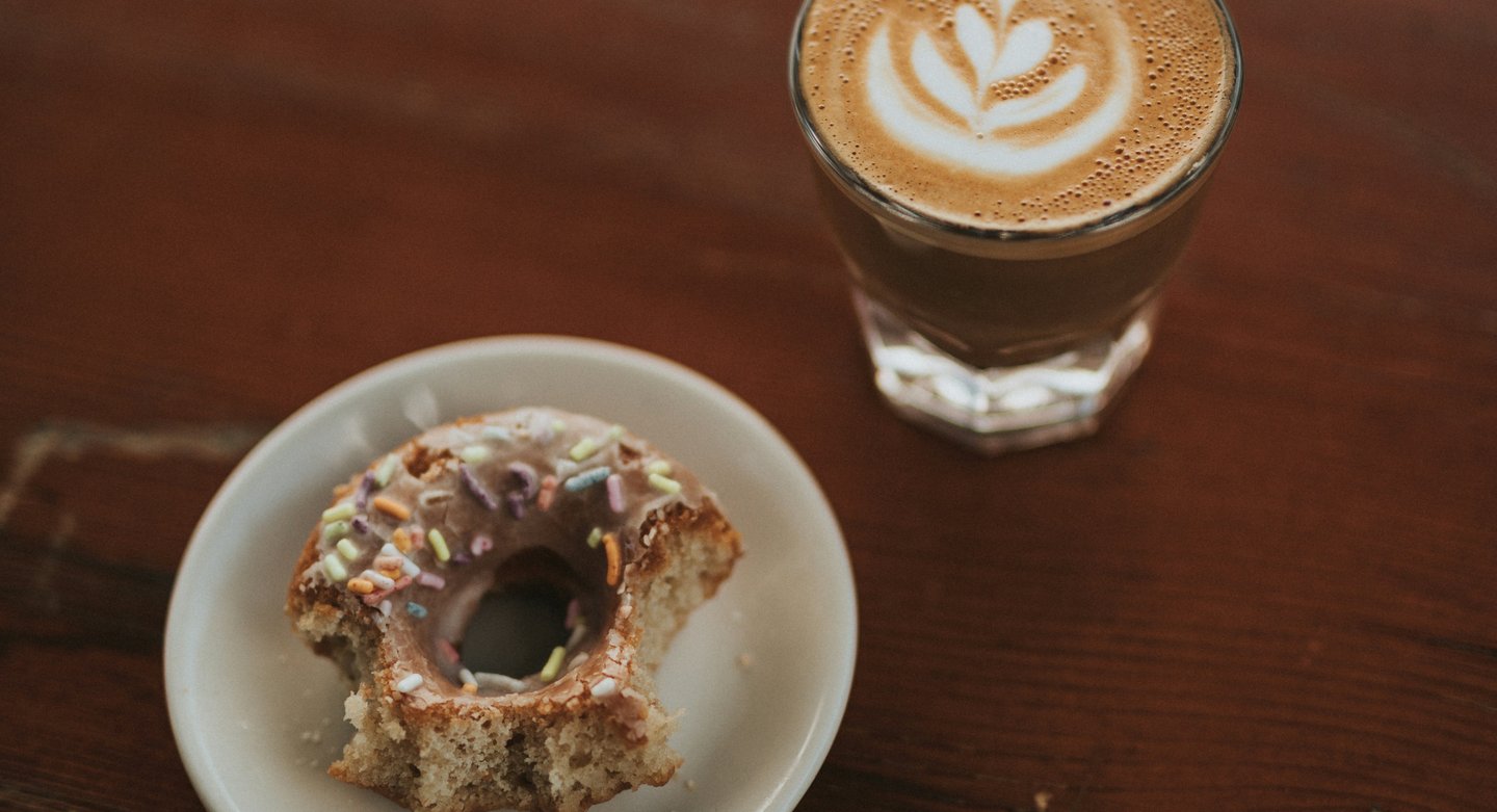 a cup of coffee and a doughnut on a table