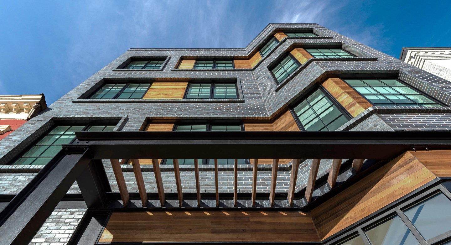 An architectural photograph of a grey brick apartment building