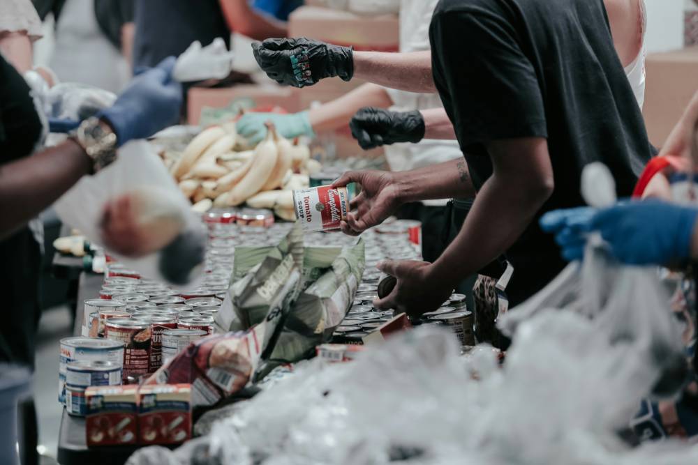 Unos voluntarios distribuyen alimentos enlatados y plátanos en un banco de alimentos
