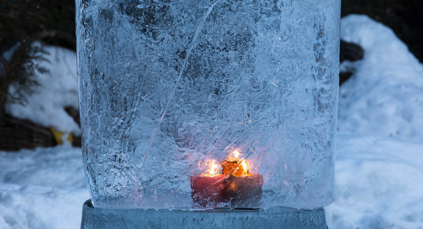 Bougie allumée figée dans la glace, symbole de mémoire et d’introspection hivernale.