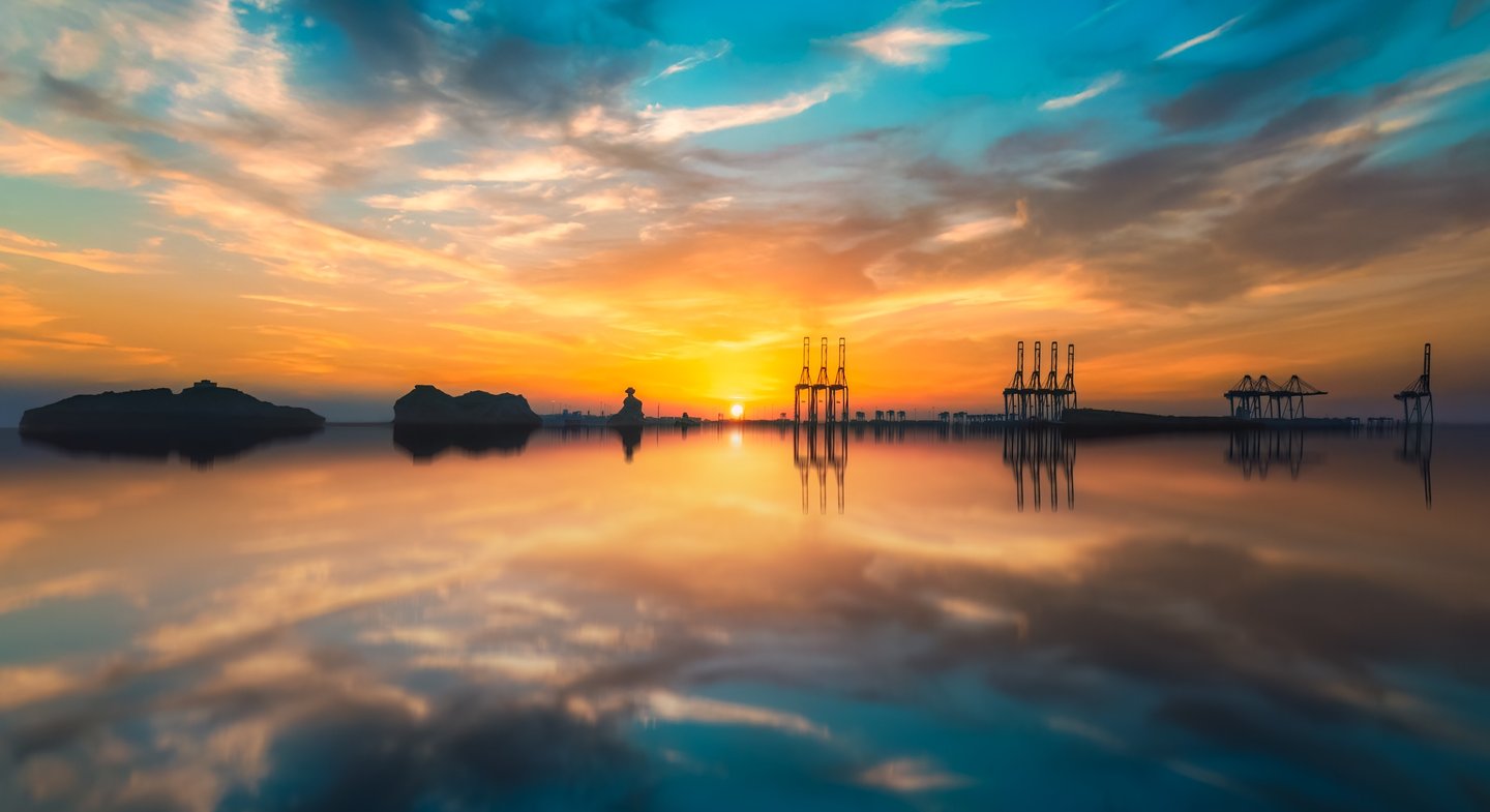 a sunset with a sailboat in the water. arbab naimat kasi , pakistan, karachi