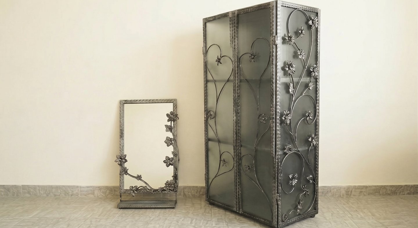 Elegant wrought iron display cabinet and matching mirror featuring intricate floral vine designs.