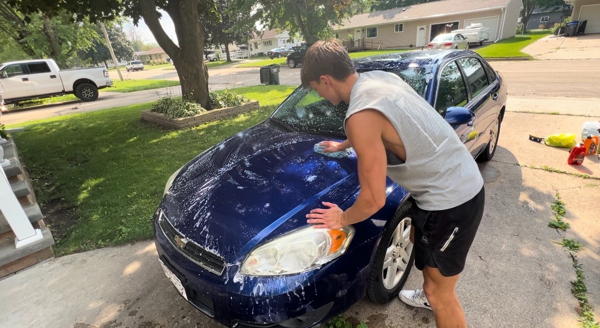 Golden mobile detailing team giving a blue sedan an exterior wash