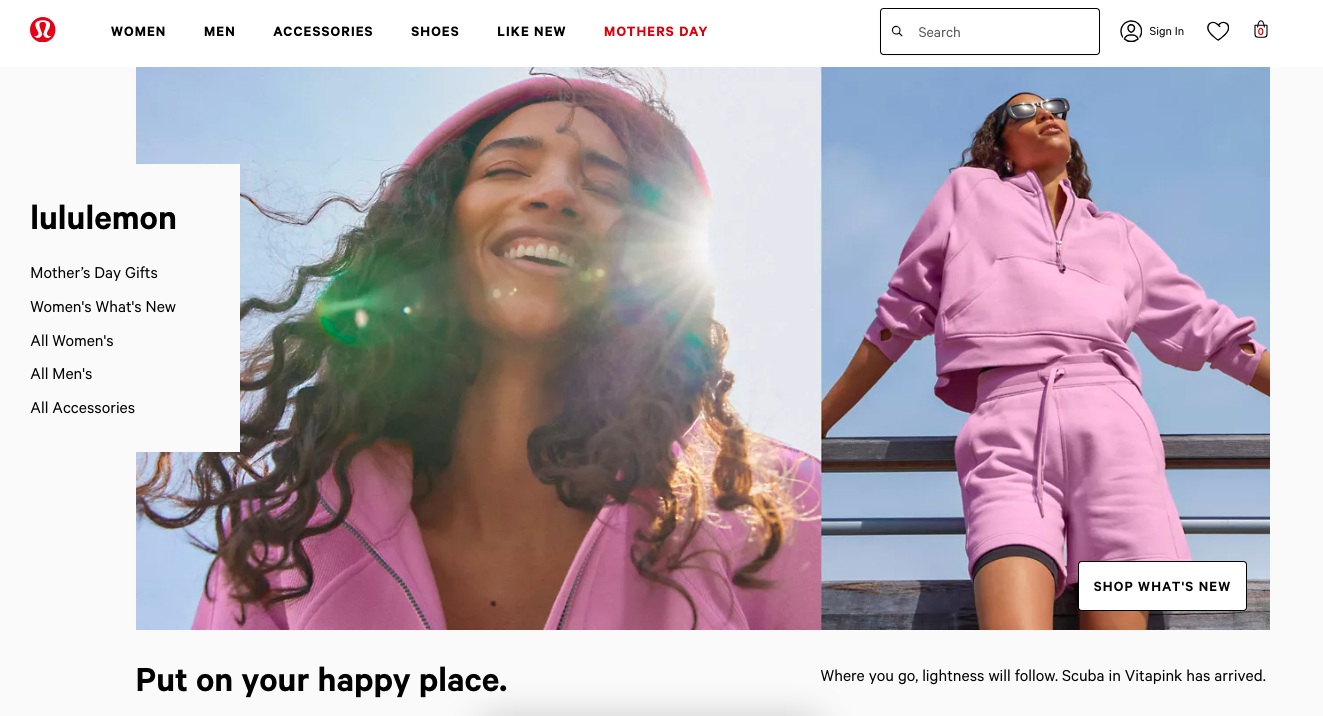 A woman with brown curly hair, smiling, wearing a pink hoodie, with the sun flaring behind her.