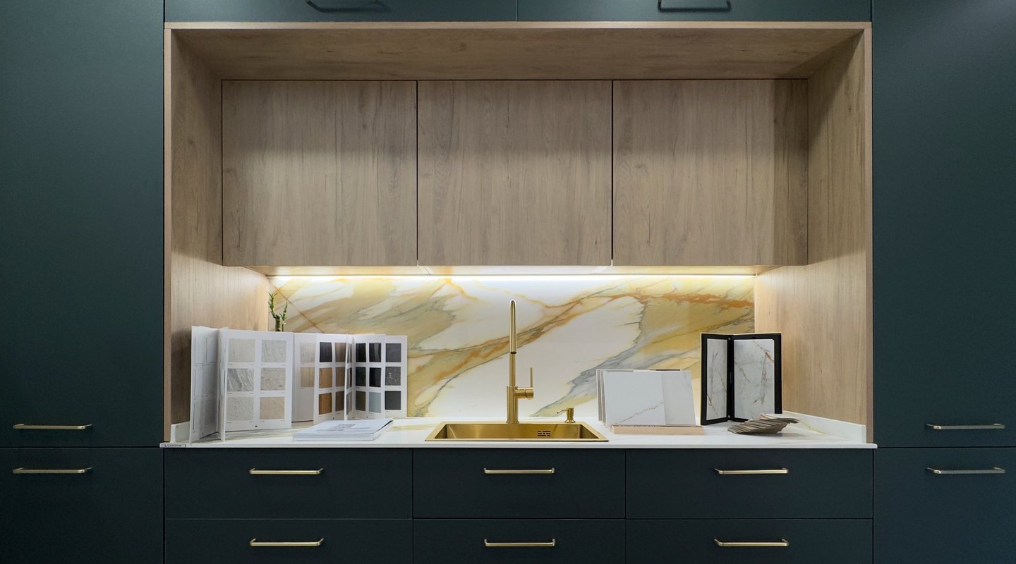 Showroom cocina moderna de lujo con mármol, tonos verdosos y grifería dorada
