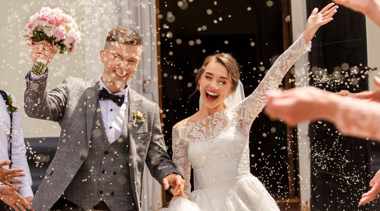 Wedding videographer in Glasgow capturing joyful confetti exit—bride and groom celebrating outside t