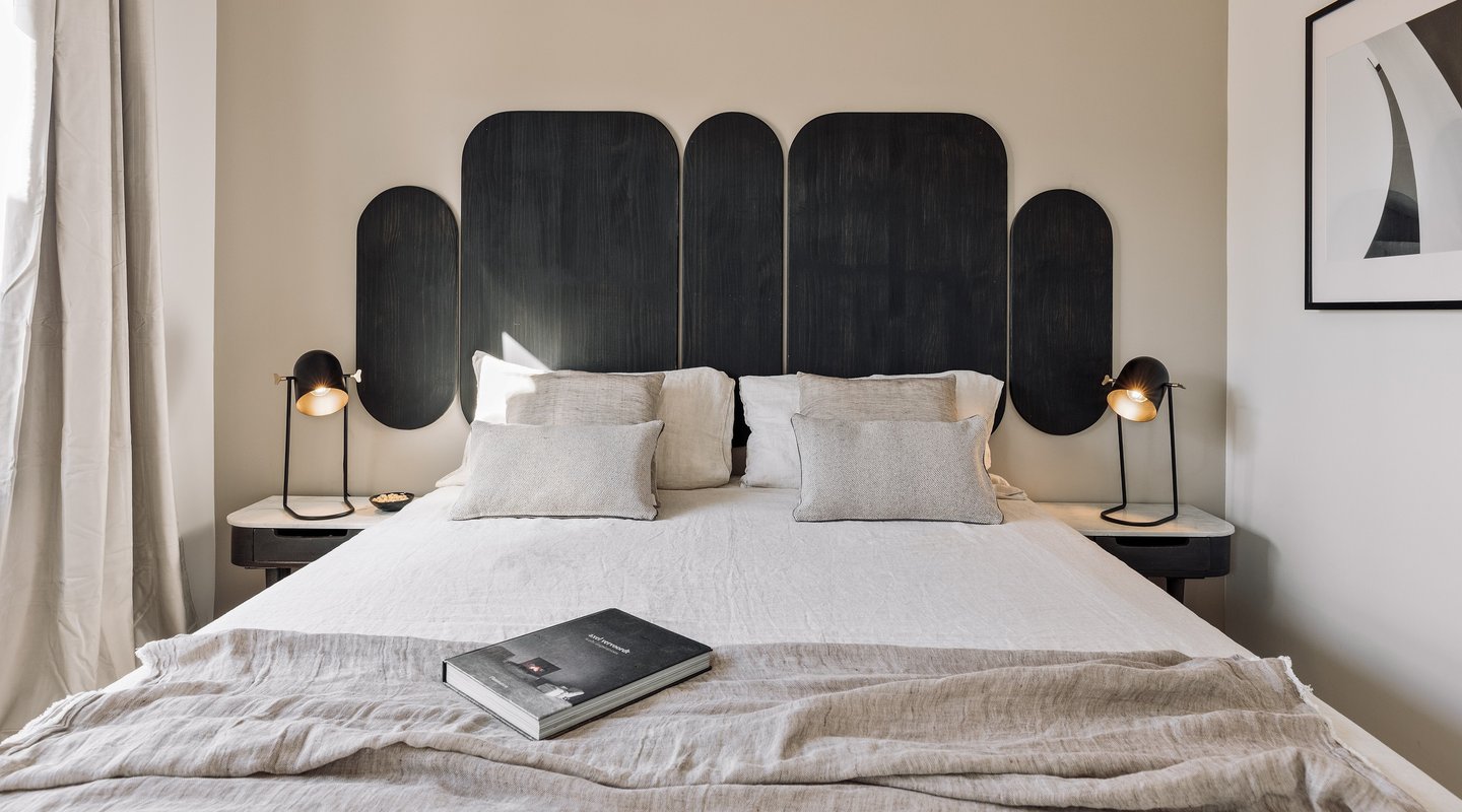 Vibrant bold black wood headboard design in a bedroom with neutral colours and natural materials