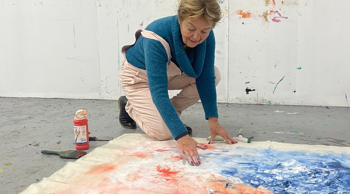 Artiste peintre travaillant une toile au sol dans son atelier