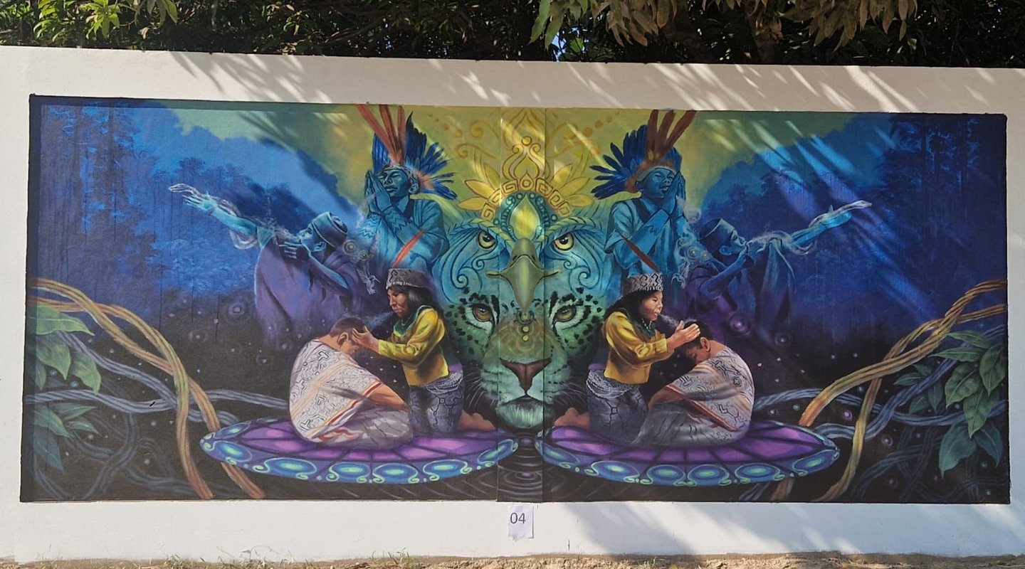A colorful outdoor mural featuring indigenous shamans, ,jaguar imagery, and blue rainforest scenery.