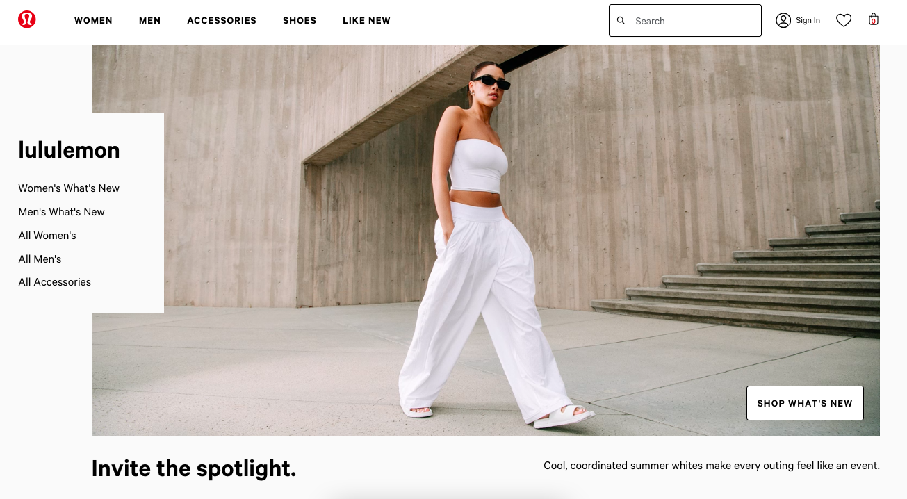 A woman wears a white tube top, white wide pants, and white sandals against a concrete wall.
