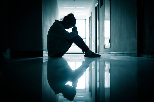 a woman sitting in the dark with anxiety