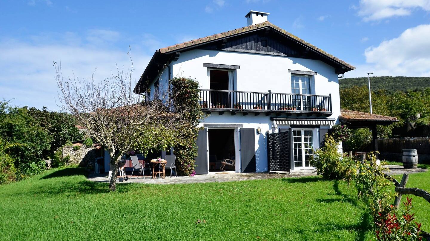 Fachada del chalet azul con un gran jardín orientado al sur