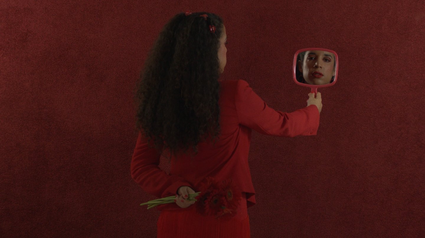 a woman in a red dress is holding a mirror