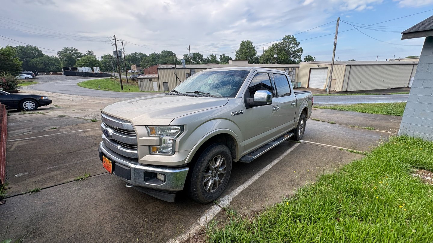 A gold F-150 Lariat pickup truck parked in an industrial lot.