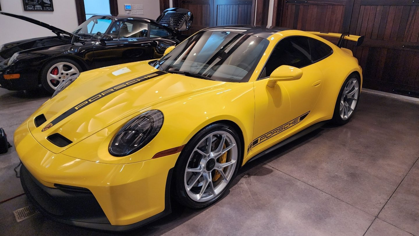 a yellow Porsche 911 GT3 parked in a garage next to a 1989 Porsche 911 Carrera awaiting appraisal