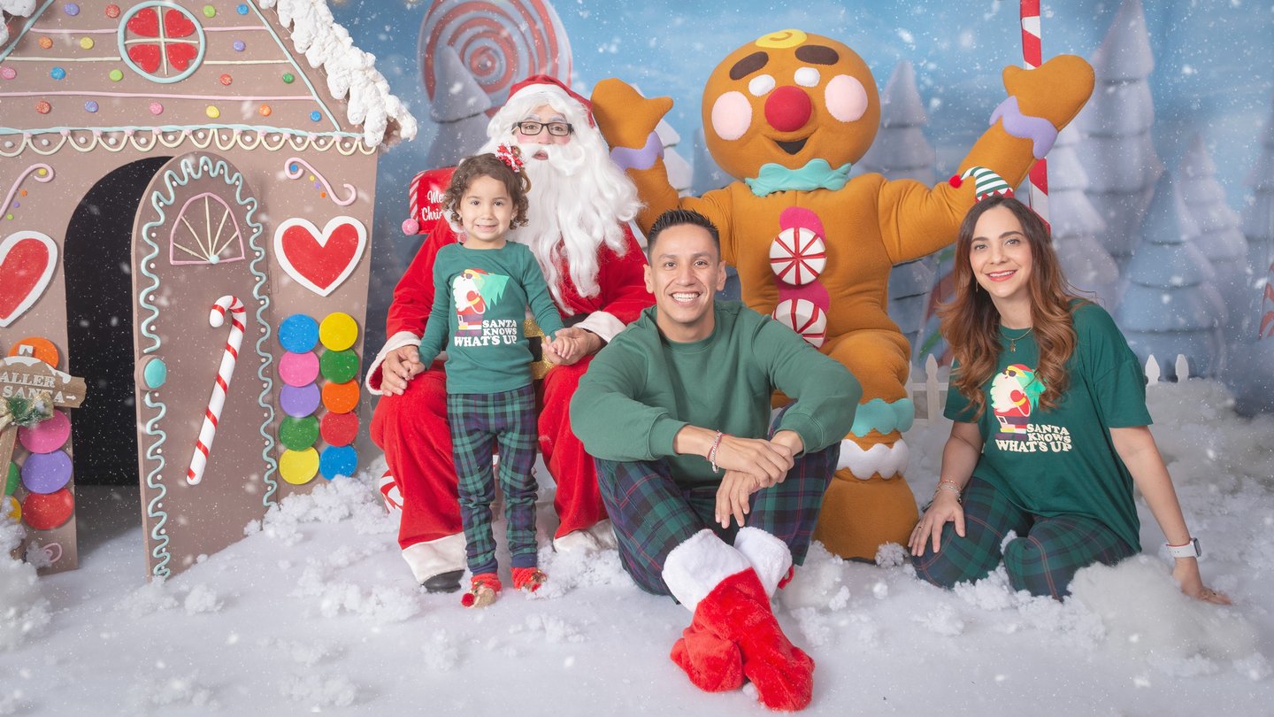 a family posing for a photo in front of a gingerbread house