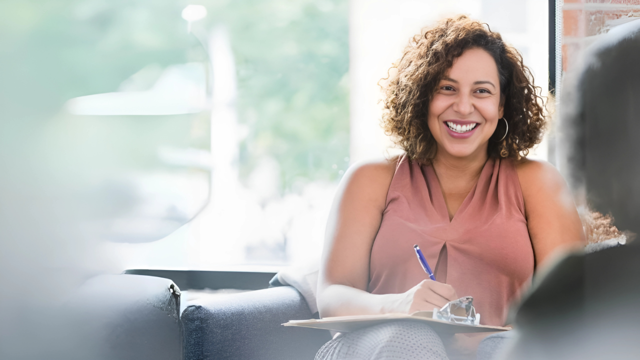 a woman sitting on a couch with a pen and a notebook