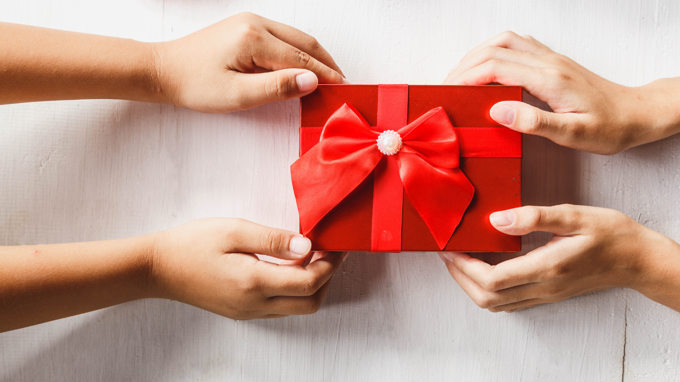 two hands holding a red gift box with a bow