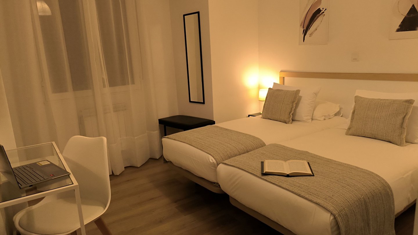 Habitación doble en Hotel Arias, Vigo, con escritorio y luz de mesilla encendida