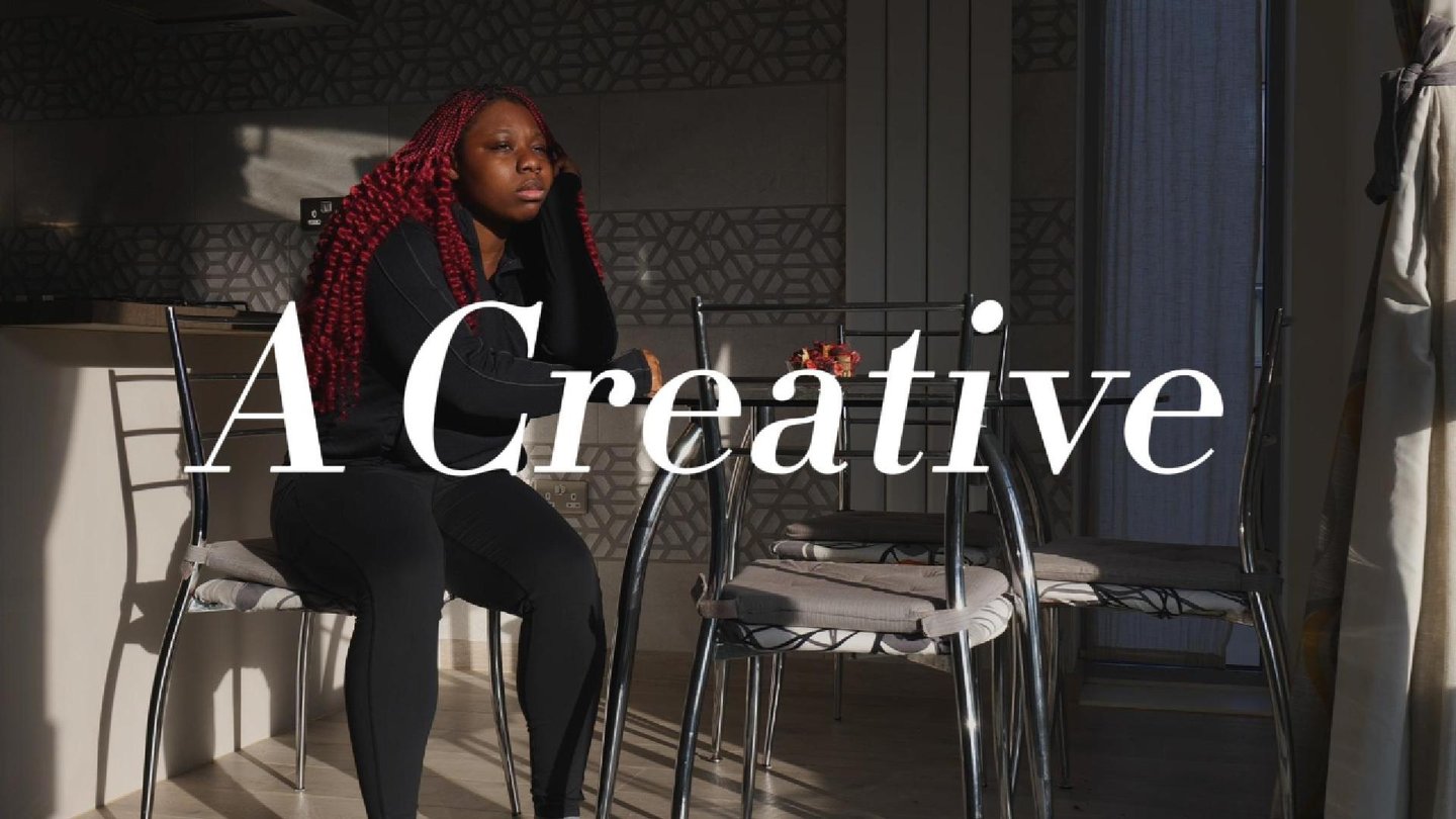 a picture of a girl with dark red hair sitting down in a video production