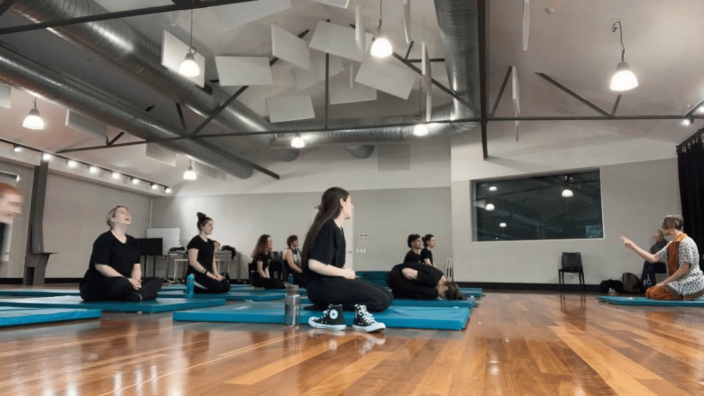 a group of people sitting on blue mats in a gym