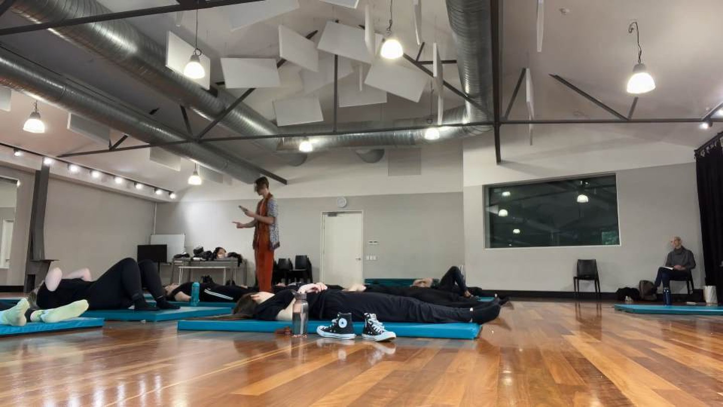 a man standing in a room with a woman on a yoga mat