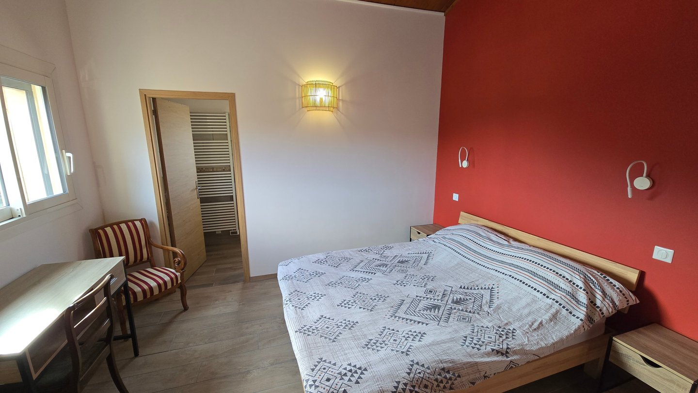 Chambre d'hôtes refaite à neuf avec lit double, chaise et bureau.