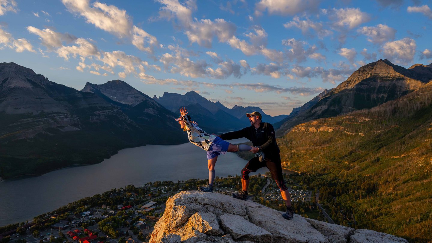 Couple posing playfully at sunrise on Bear’s Hump overlooking Upper Waterton Lake.