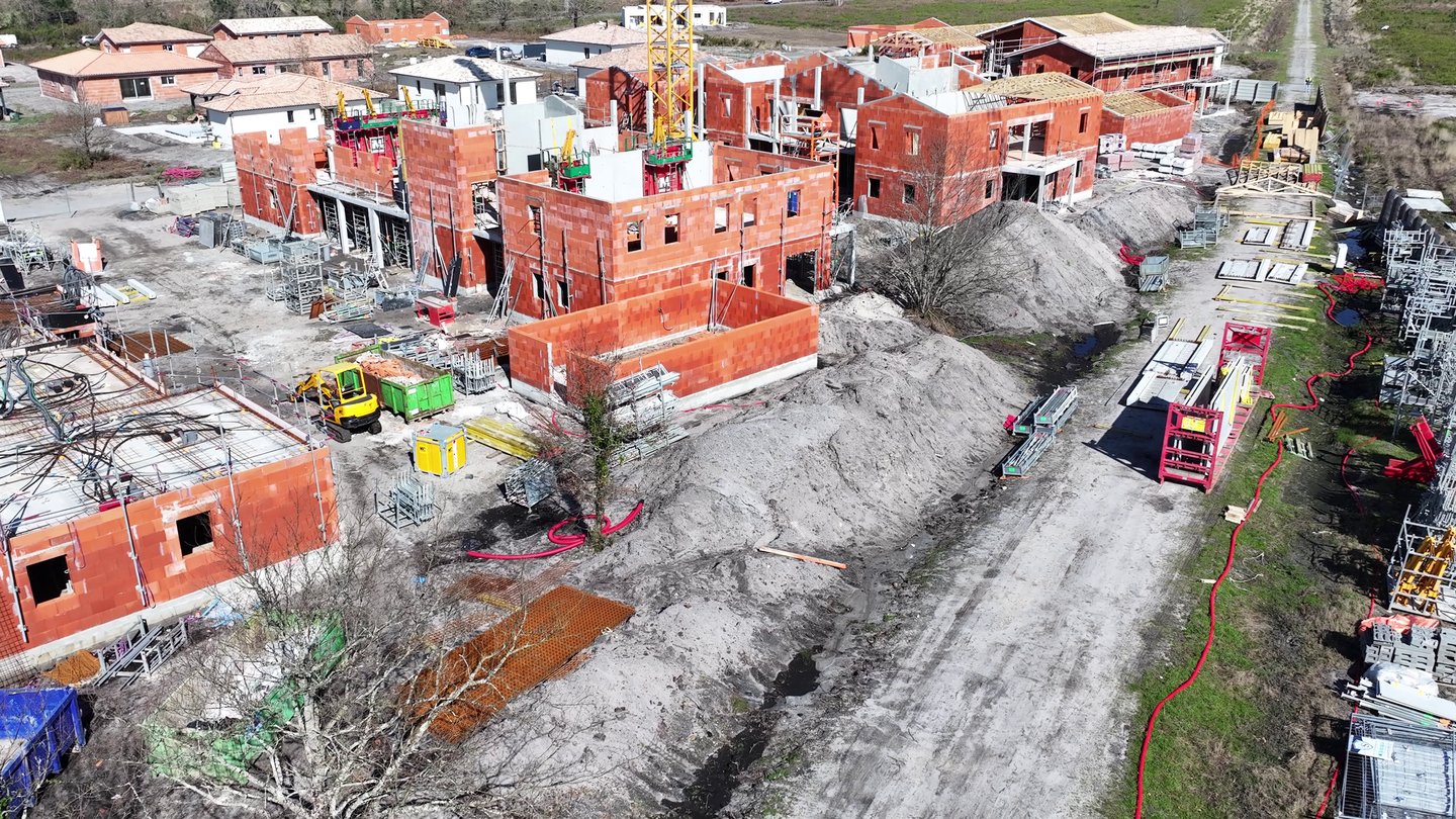 Vue aérienne d'un chantier résidentiel avec des maisons en brique rouge des échafaudages et une grue