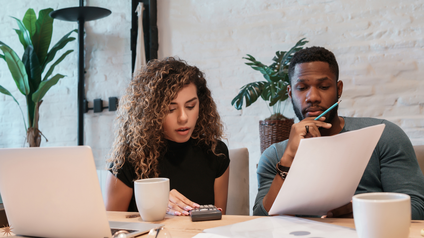 Young couple reviewing financial documents and using a calculator to plan their household budget at home.