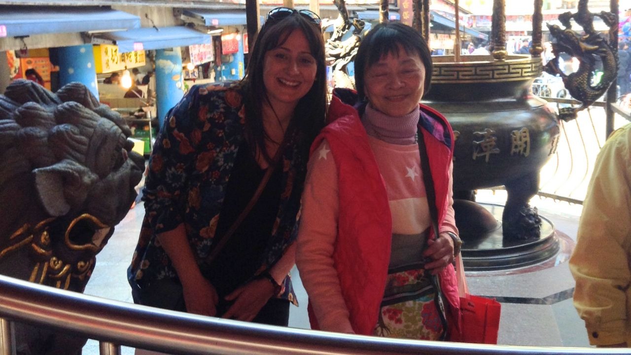 Autora posando com uma senhora local no templo Qingan, em Keelung.