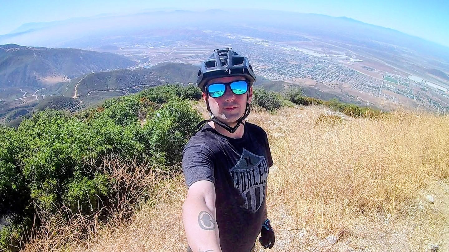 mountain biker on top of foothills wearing sunglasses and helmet